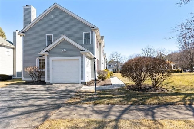 view of home's exterior featuring aphalt driveway, a garage, and a chimney