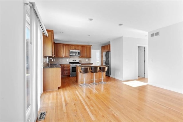 kitchen featuring a kitchen breakfast bar, tasteful backsplash, visible vents, and appliances with stainless steel finishes