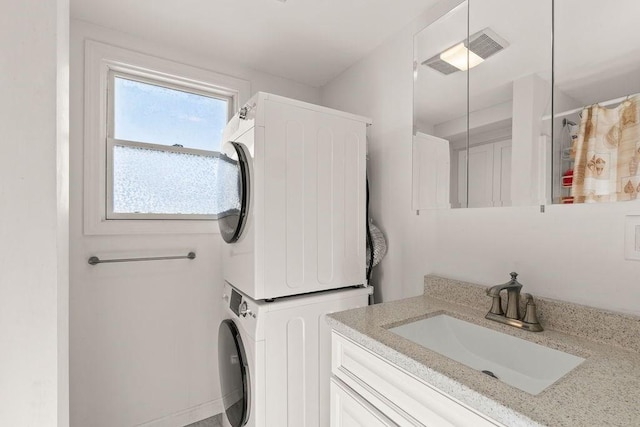 laundry room with laundry area, stacked washing maching and dryer, and a sink