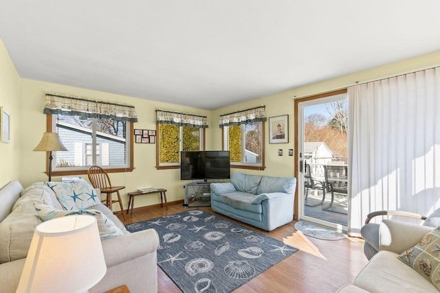 living area featuring baseboards, a healthy amount of sunlight, and wood finished floors