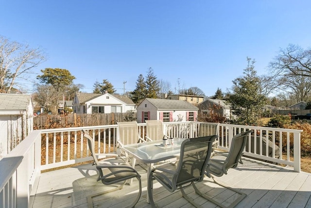 wooden deck featuring outdoor dining area, a residential view, an outbuilding, and fence