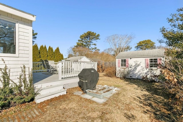 view of yard featuring a deck, an outbuilding, and fence