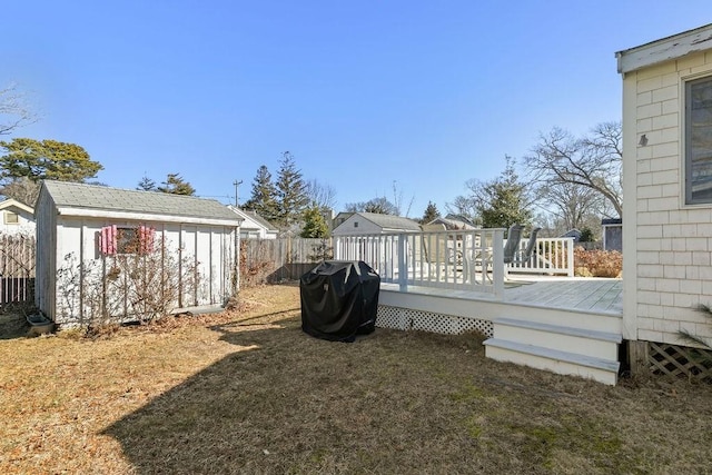 view of yard featuring a storage shed, an outbuilding, fence, and a wooden deck