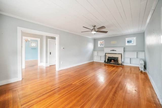 unfurnished living room featuring ceiling fan, a tiled fireplace, light hardwood / wood-style floors, and ornamental molding