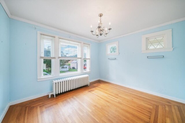 unfurnished room featuring radiator heating unit, light hardwood / wood-style flooring, a notable chandelier, and ornamental molding