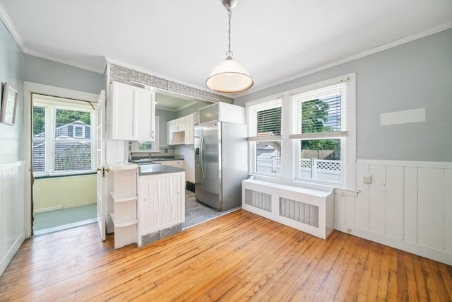 kitchen with white cabinets, light hardwood / wood-style floors, pendant lighting, stainless steel fridge with ice dispenser, and kitchen peninsula