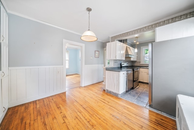 kitchen featuring hanging light fixtures, ornamental molding, light wood-type flooring, white cabinetry, and stainless steel appliances