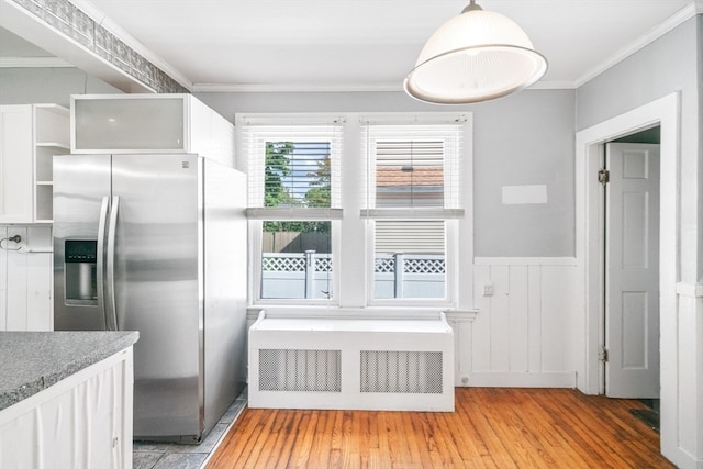 kitchen featuring white cabinets, light wood-type flooring, stainless steel fridge, and radiator heating unit