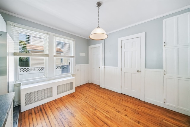 unfurnished dining area featuring radiator, light hardwood / wood-style floors, and crown molding