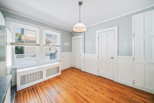 interior space with ornamental molding, radiator heating unit, and light hardwood / wood-style floors