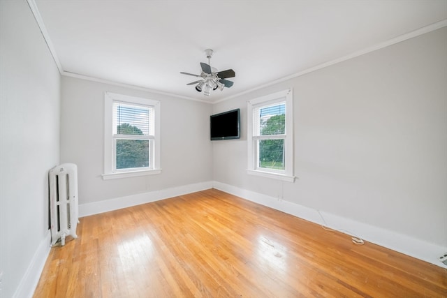 empty room featuring ceiling fan, light hardwood / wood-style flooring, radiator heating unit, and a healthy amount of sunlight