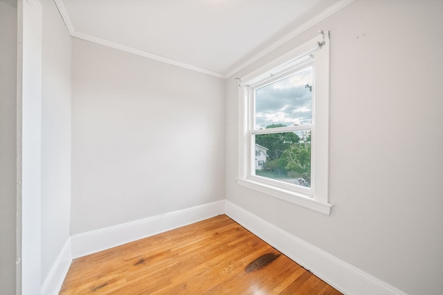 empty room featuring plenty of natural light, crown molding, and wood-type flooring