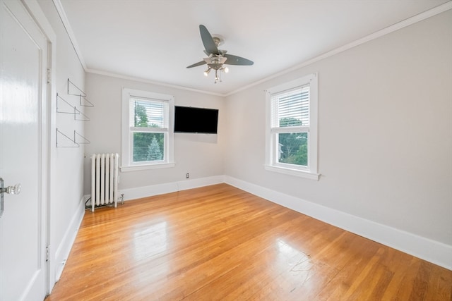 empty room with light hardwood / wood-style floors, ornamental molding, ceiling fan, and radiator heating unit