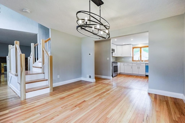 47 Forest St, Franklin, MA 02038 - unfurnished living room featuring a chandelier, light wood-style flooring, stairway, baseboards, and a sink