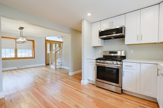 47 Forest St, Franklin, MA 02038 - kitchen featuring appliances with stainless steel finishes, light countertops, light wood-type flooring, white cabinetry, and baseboards