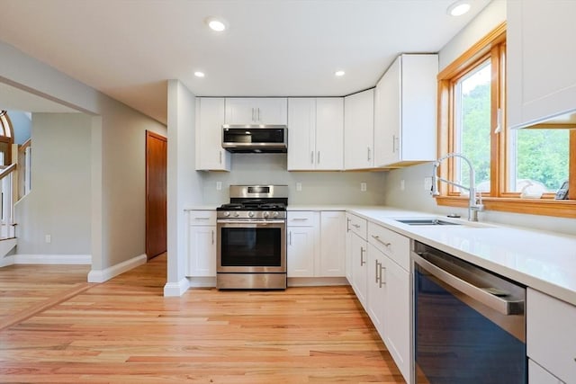 47 Forest St, Franklin, MA 02038 - kitchen with appliances with stainless steel finishes, a sink, light wood-style floors, light countertops, and white cabinetry