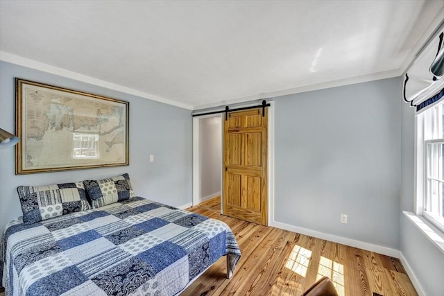 274 Morton Rd, Chatham, MA 02659 - bedroom with a barn door, light wood-type flooring, baseboards, and ornamental molding