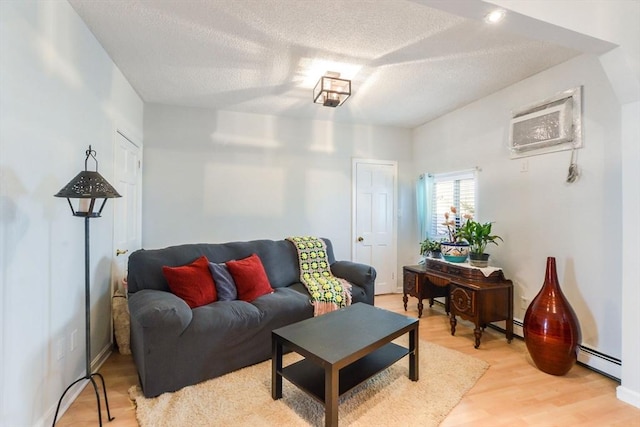 living room with hardwood / wood-style flooring, a baseboard radiator, a textured ceiling, and a wall mounted AC