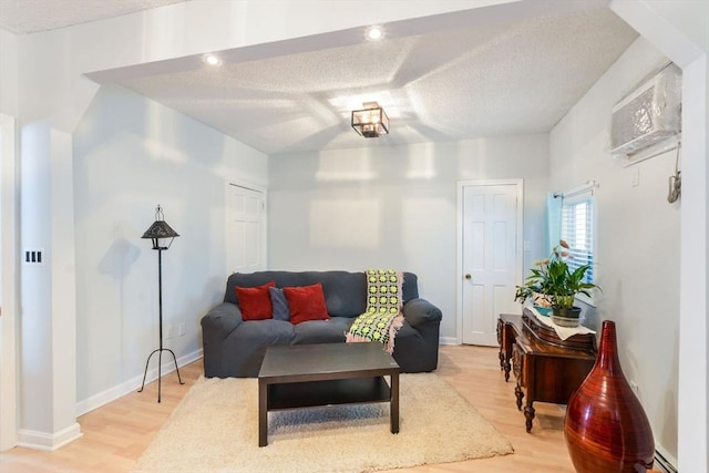 living room featuring hardwood / wood-style flooring, a wall mounted AC, and a textured ceiling