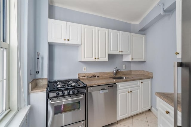 kitchen featuring appliances with stainless steel finishes, white cabinetry, light stone counters, and light tile patterned flooring