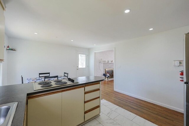 kitchen with dark countertops, baseboards, recessed lighting, electric stovetop, and a fireplace