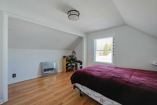 bedroom with vaulted ceiling and wood finished floors