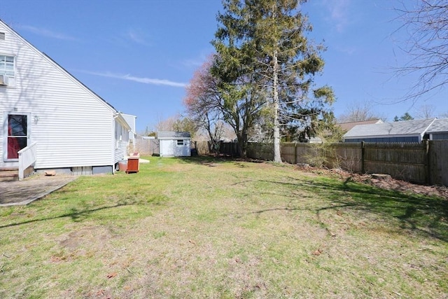 view of yard featuring a fenced backyard, an outdoor structure, entry steps, and a storage shed