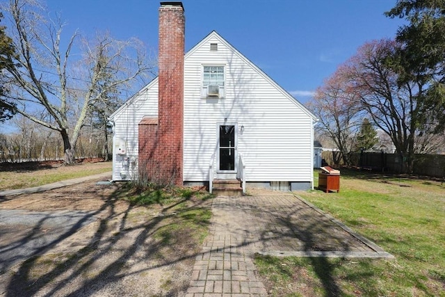 rear view of property featuring a chimney, fence, a yard, and entry steps