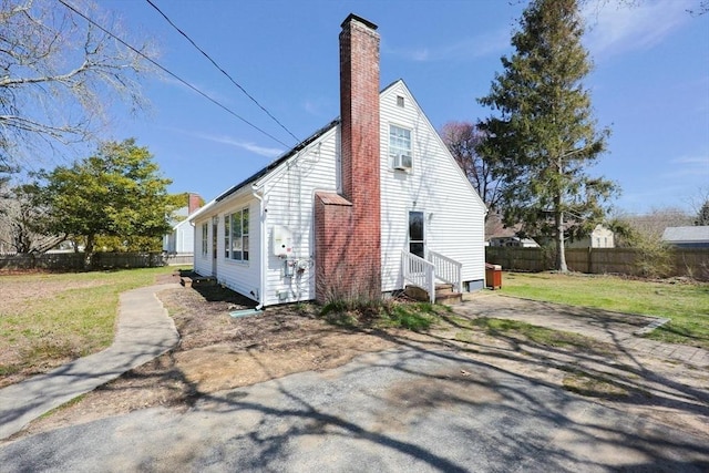 rear view of house featuring a yard, a chimney, and fence