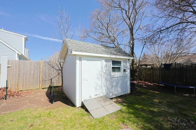 view of shed with fence and a trampoline