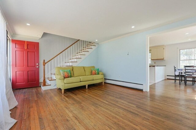 living area featuring a baseboard heating unit, stairs, ornamental molding, and wood-type flooring