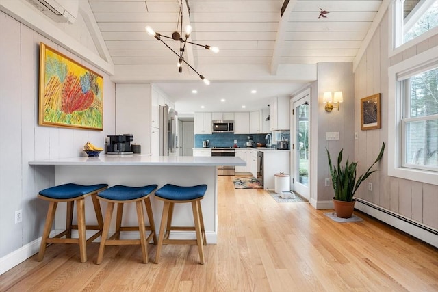 kitchen featuring lofted ceiling with beams, light countertops, decorative backsplash, stainless steel appliances, and a baseboard radiator