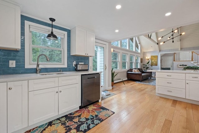 kitchen with lofted ceiling with beams, open floor plan, light wood-style flooring, dishwashing machine, and a sink