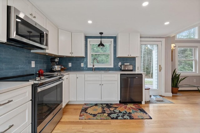 kitchen with light wood-style flooring, white cabinetry, light countertops, a sink, and stainless steel appliances