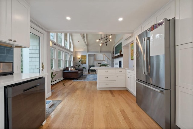 kitchen with white cabinets, light countertops, a baseboard radiator, appliances with stainless steel finishes, and a peninsula