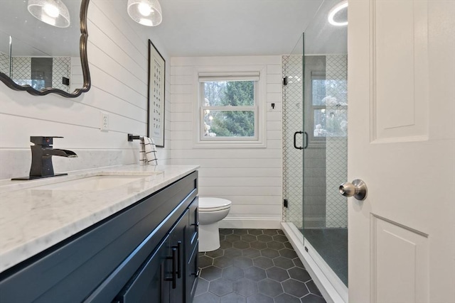 full bathroom with vanity, toilet, a stall shower, wooden walls, and tile patterned floors