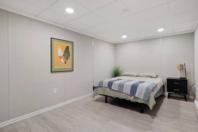 bedroom with baseboards, recessed lighting, a drop ceiling, and wood finished floors