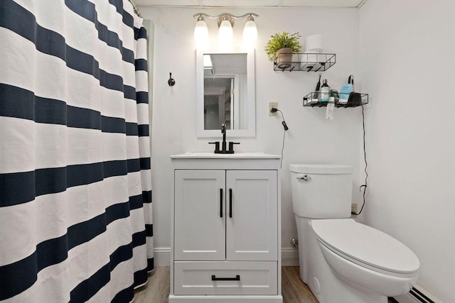 full bathroom featuring baseboards, toilet, vanity, wood finished floors, and a baseboard heating unit