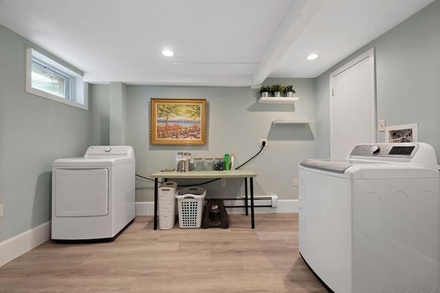clothes washing area featuring baseboard heating, light wood-style floors, washing machine and clothes dryer, and baseboards