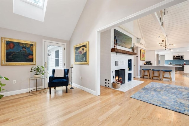 sitting room with light wood-style flooring, a skylight, a fireplace with flush hearth, and baseboards