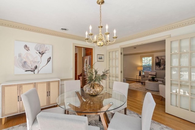 dining room featuring a chandelier, light wood finished floors, and baseboard heating