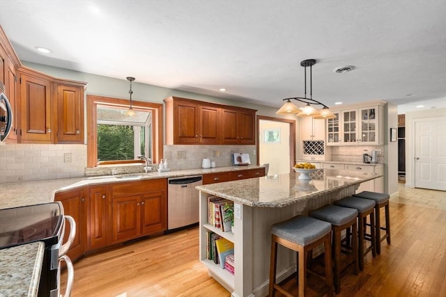 kitchen featuring stainless steel dishwasher, a sink, backsplash, a kitchen breakfast bar, and electric range oven