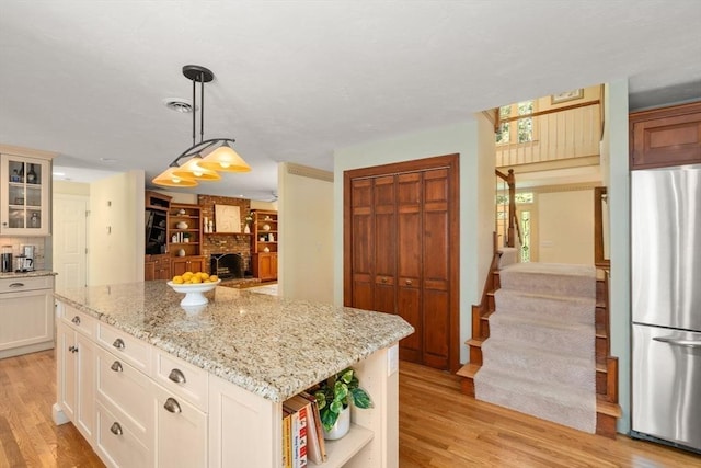kitchen featuring freestanding refrigerator, open shelves, light wood-type flooring, and glass insert cabinets
