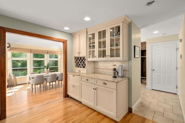 bar with backsplash, recessed lighting, baseboards, and light stone finish floors