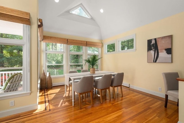 dining space featuring plenty of natural light, vaulted ceiling, light wood finished floors, and baseboards