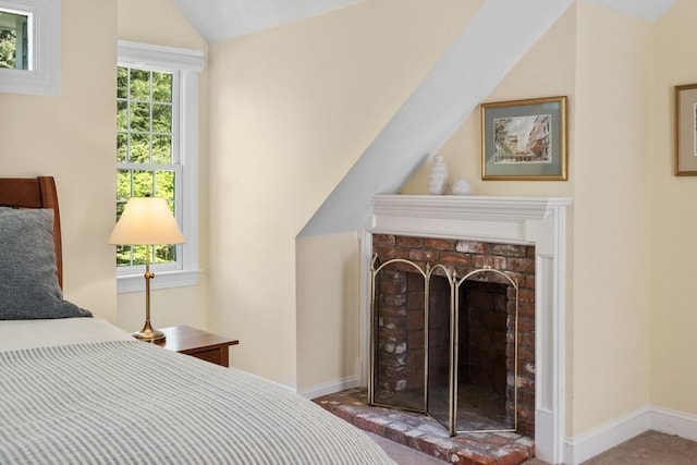 bedroom featuring vaulted ceiling, baseboards, and a fireplace