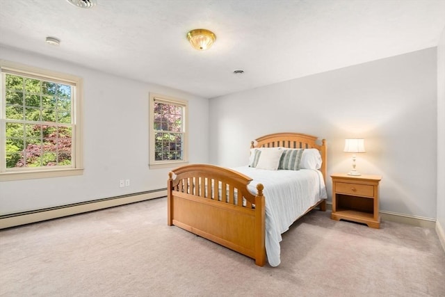 carpeted bedroom with baseboard heating, multiple windows, and baseboards