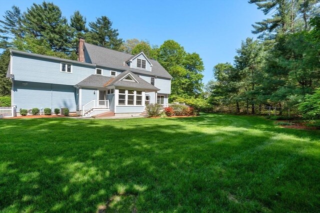 back of property with a lawn and a chimney