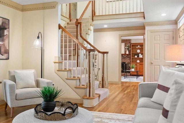 stairs featuring wood finished floors, a brick fireplace, baseboards, and recessed lighting