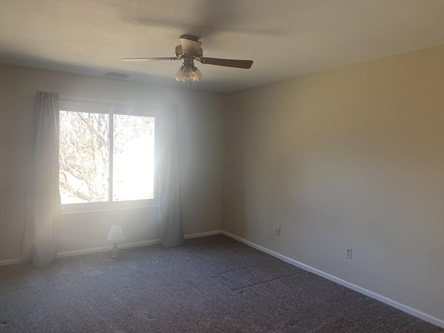 empty room featuring dark colored carpet, baseboards, and a ceiling fan